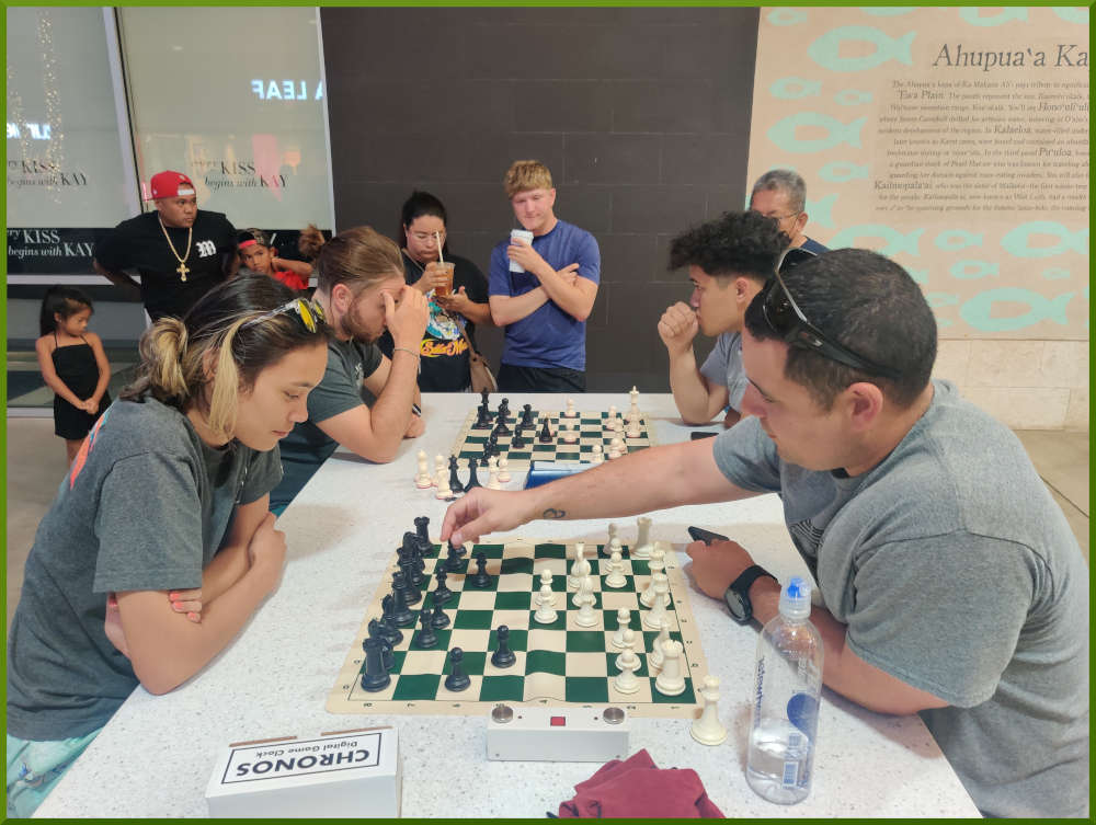 May 24th, 2022. Ka Makana Alii chess meetup. Girl getting lesson from Phil (near board). Ari vs Christian (far board).
