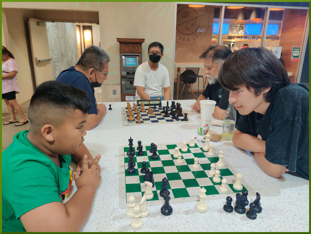 May 24th, 2022. Ka Makana Alii chess meetup. Two young boys playing (near board). Ceasar vs Chet (far board).