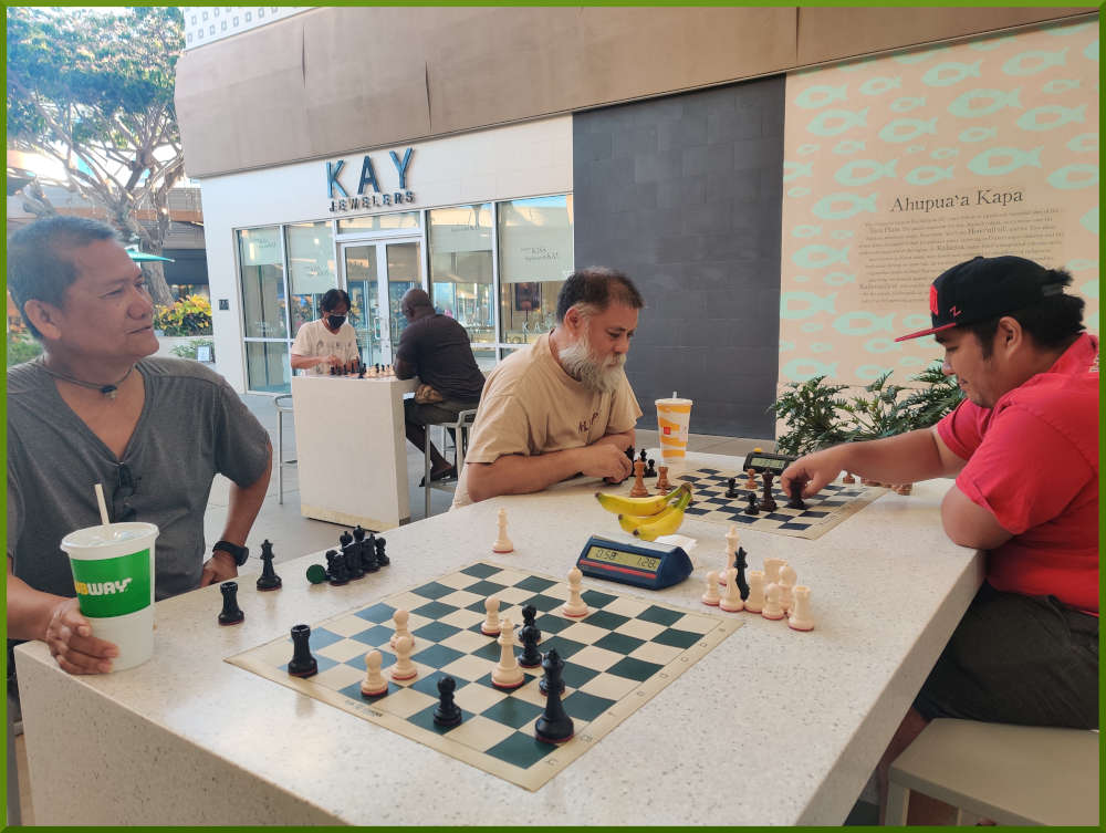 August 2nd, 2022. Ka Makana Alii chess meetup. Edgar waiting for opponent (near board). Chet vs Ceazar (far board). Regie vs Ramon (far table).